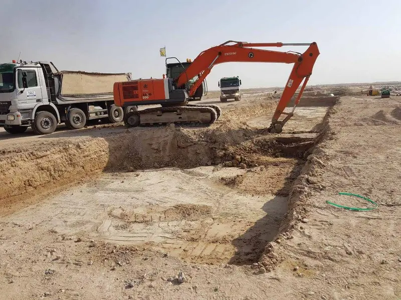 Excavator digging a trench next to a tipper truck