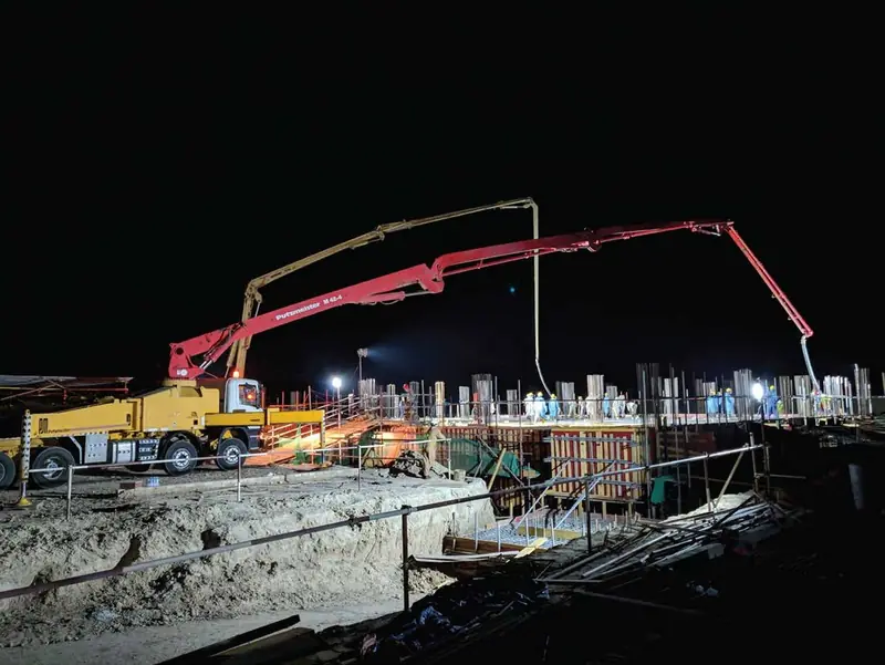 Concrete pump working on a construction site at night