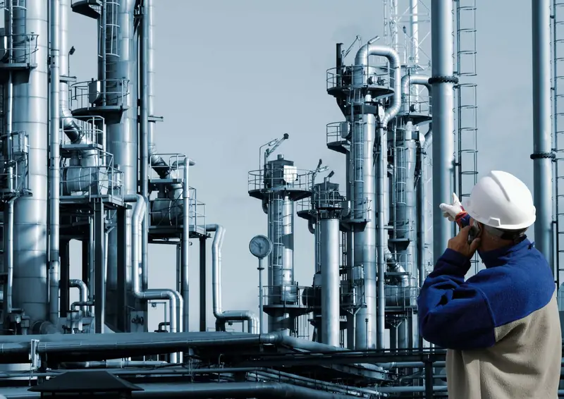 Oil and gas process columns with an engineer in a hard hat inspecting the facility