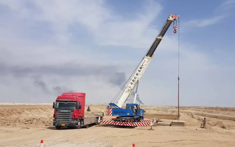 Mobile crane and truck on a desert project site