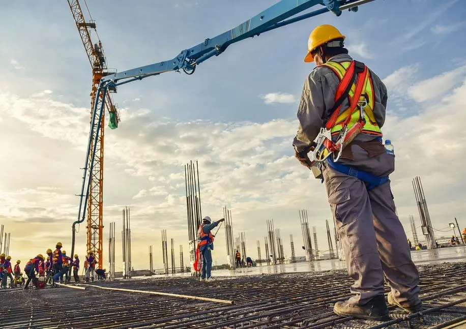 Construction supervisor in safety harness overseeing a concrete pour